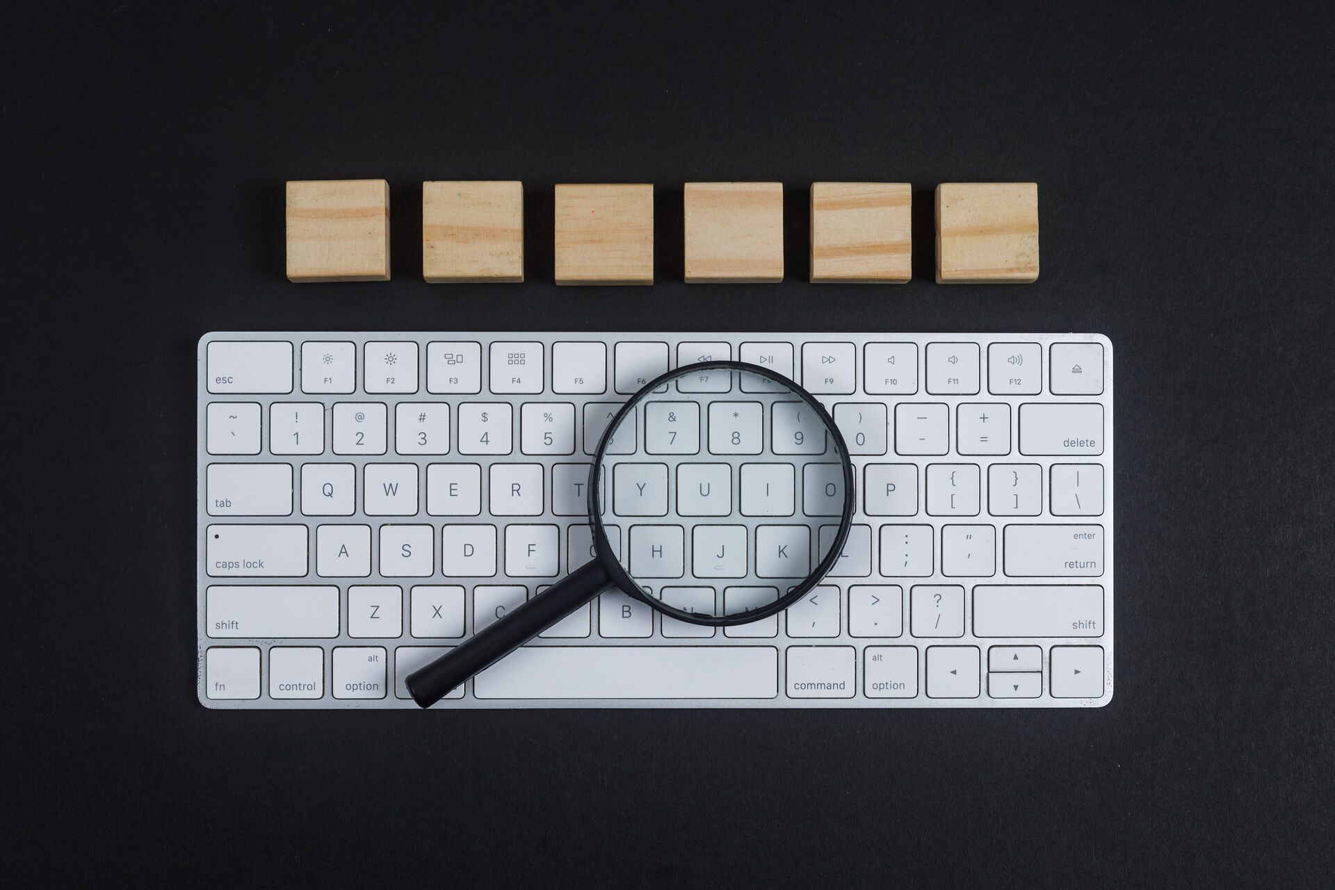 Conceptual of research with keyboard, magnifier, wooden cubes on black desk background flat lay. horizontal image